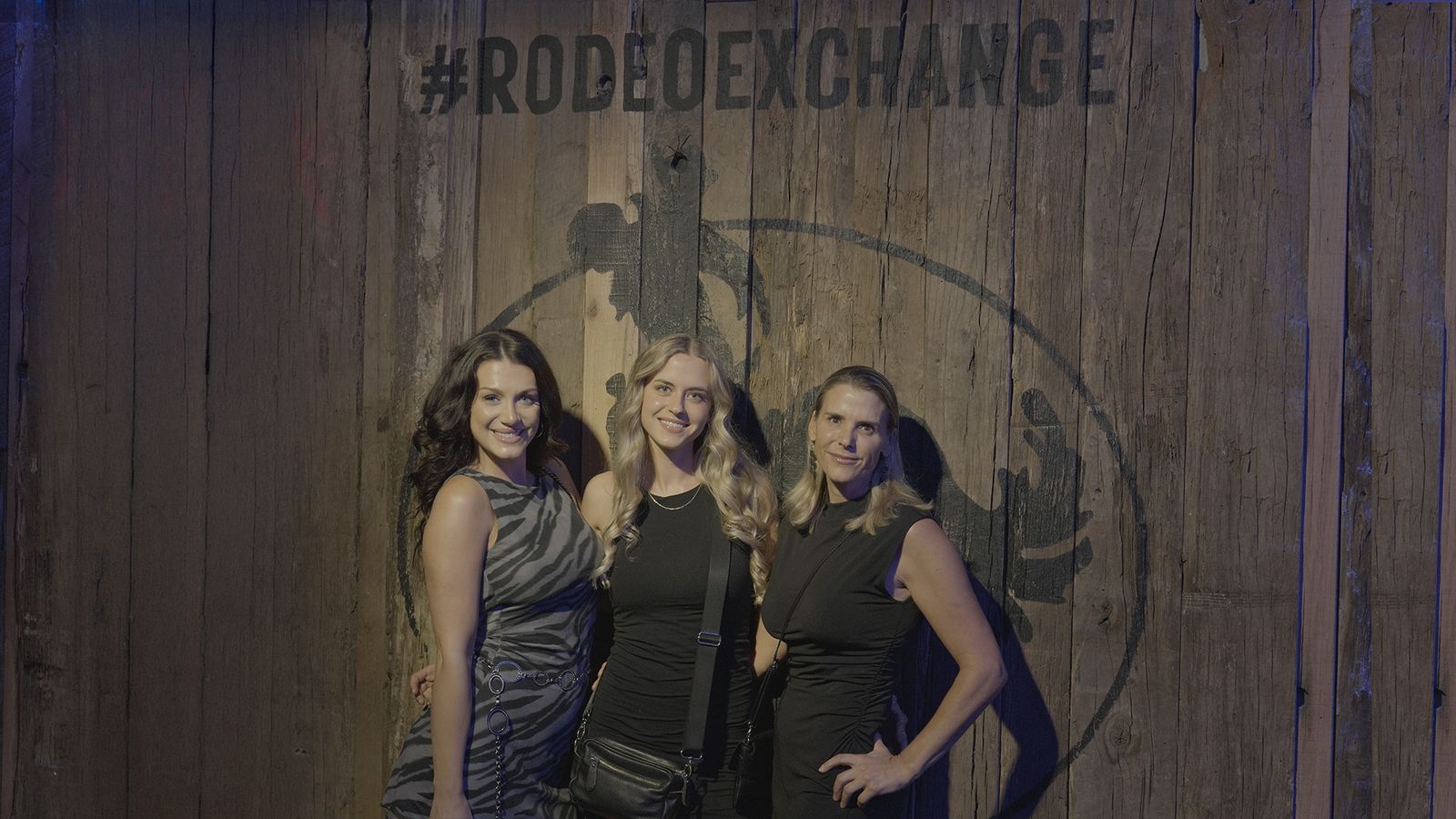 Three friends posing at the #RODEOEXCHANGE wall