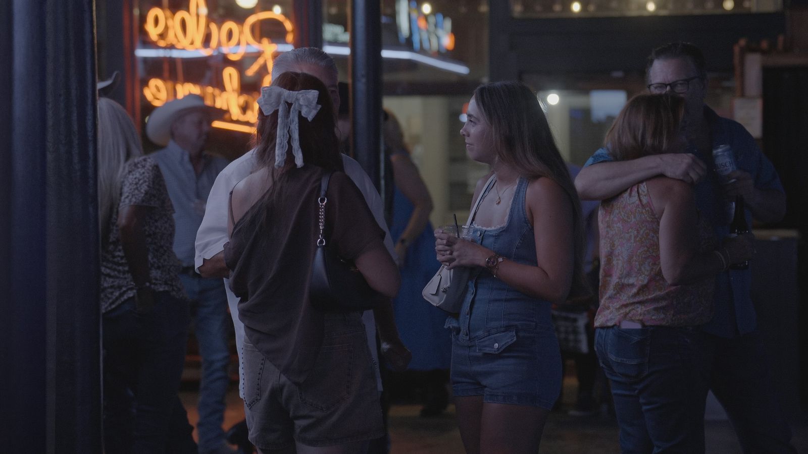 Guests talking by the neon Rodeo Exchange sign